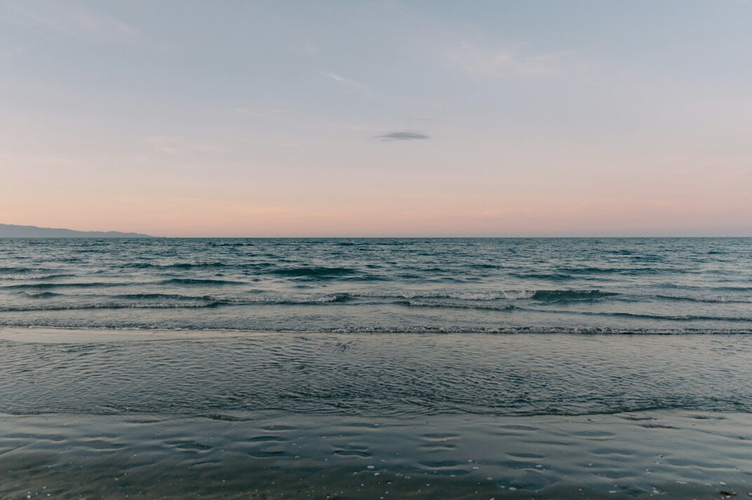 Wide sandy beach with calm sea at sunset